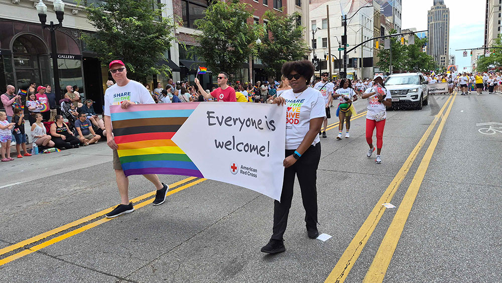 a pride parade with two people holding a sign that says ,"Everyone is welcome!"