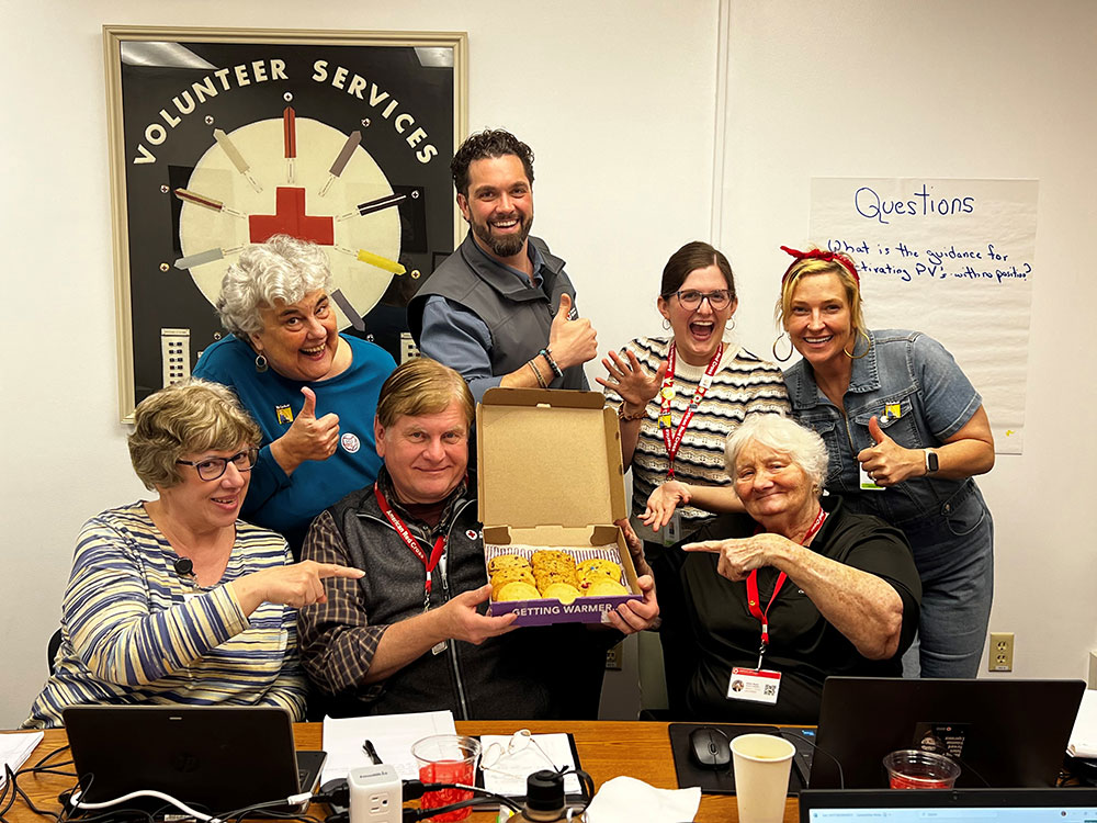 group picture of Red Cross staff members giving a thumbs up and holding up an open box of cookies.