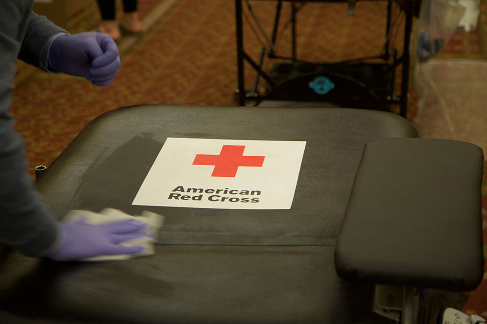 a Red Cross blood donation chair being wiped down with a cleaning cloth.