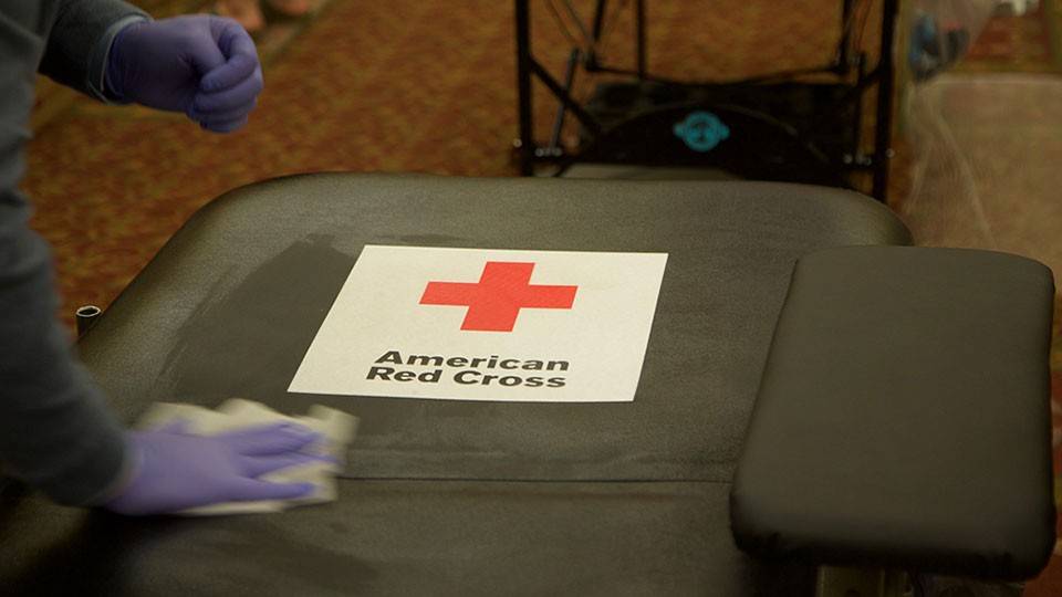 a Red Cross blood donation chair being wiped down with a cleaning cloth.