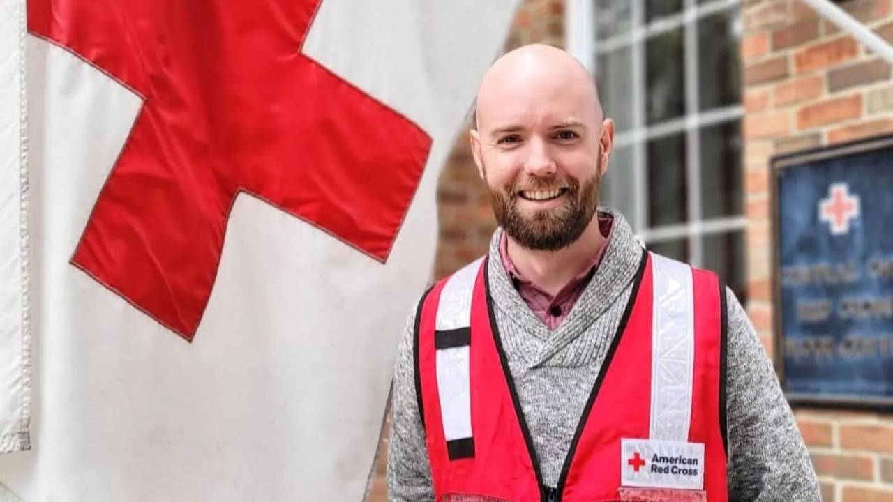 atticus garden standing next to red cross flag