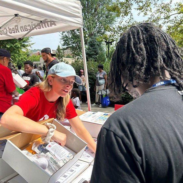 Red Cross volunteer speaking with person at event.