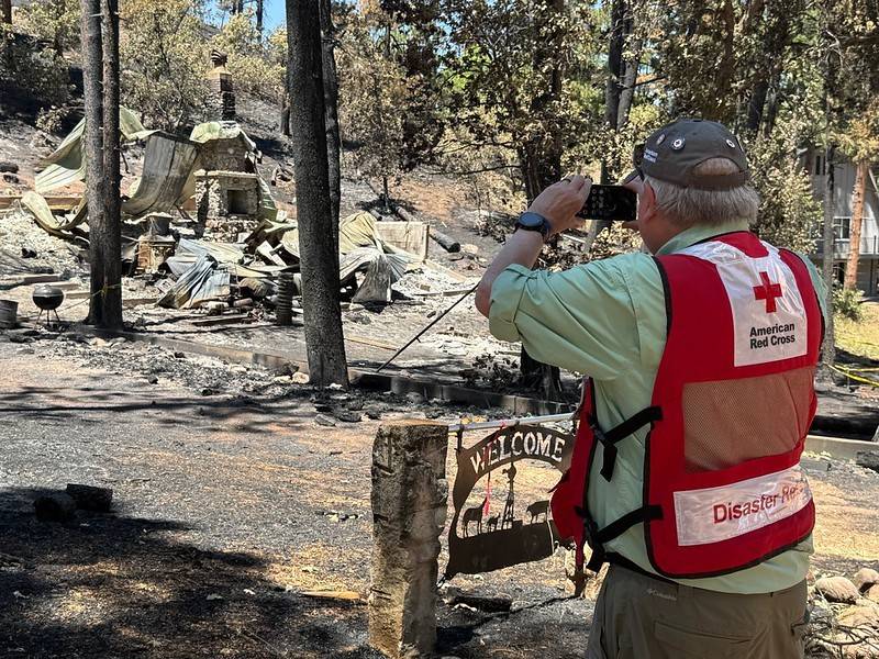 A Red Cross volunteer photographs damage from a wildfire