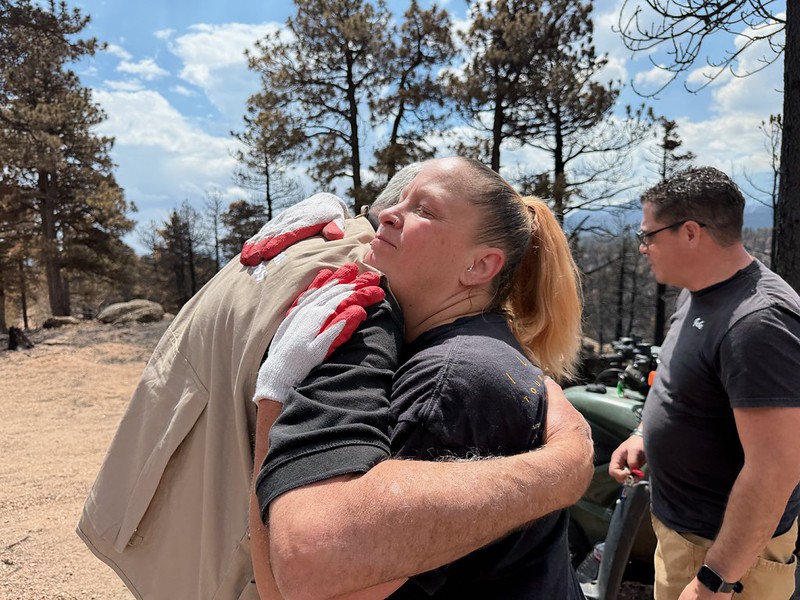 A man in a Red Cross vest hugs a woman