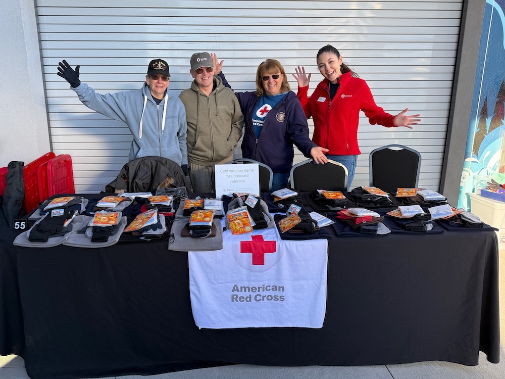 Four volunteers stand behind a table full of supplies