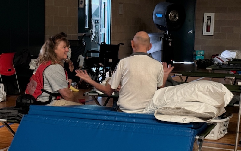A woman talks with a man inside of a shelter dormitory