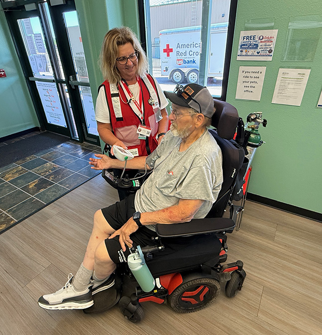A woman assists a man in an electric wheelchair