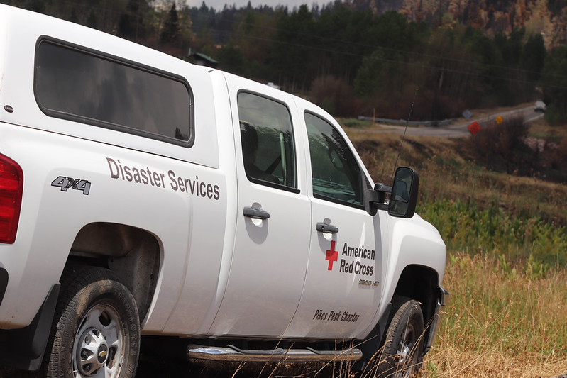 Red Cross branded truck parked in front of a field and burn scar
