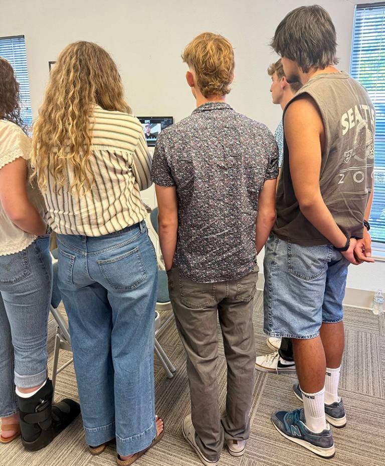 People gathered around a screen having a conversation with a man on a video call