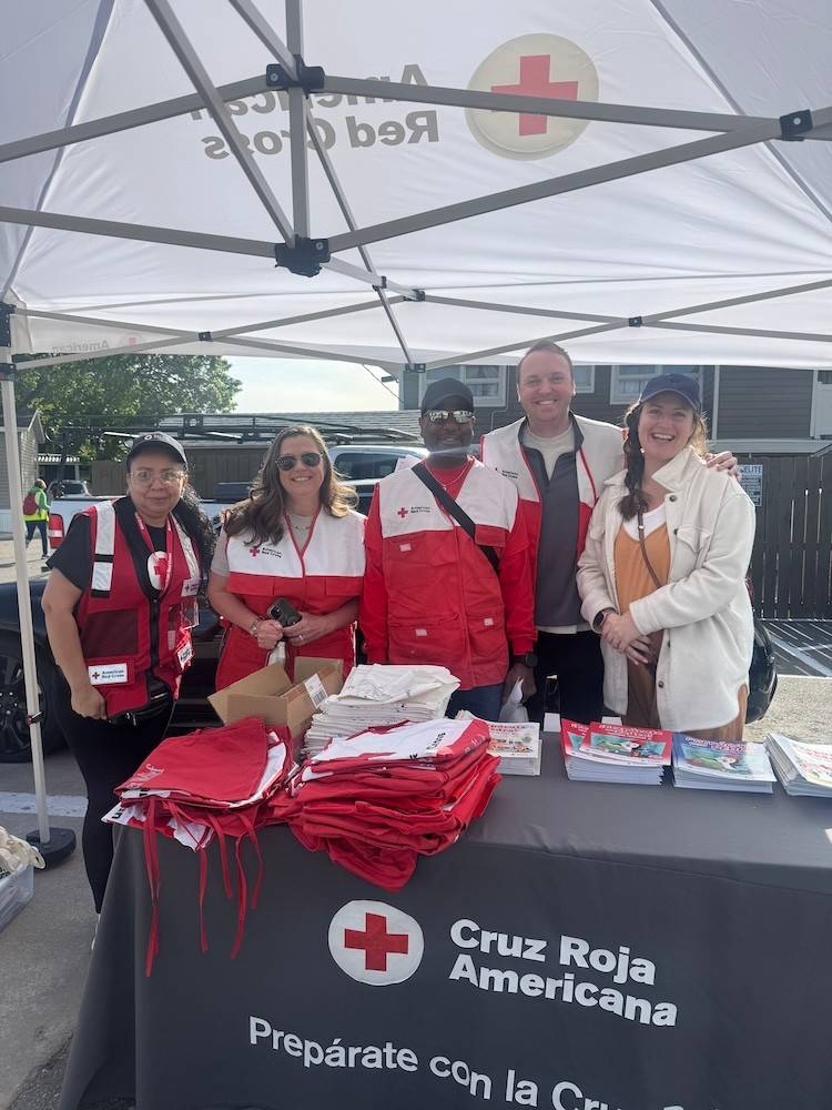 Several people stand behind a Red Cross branded table