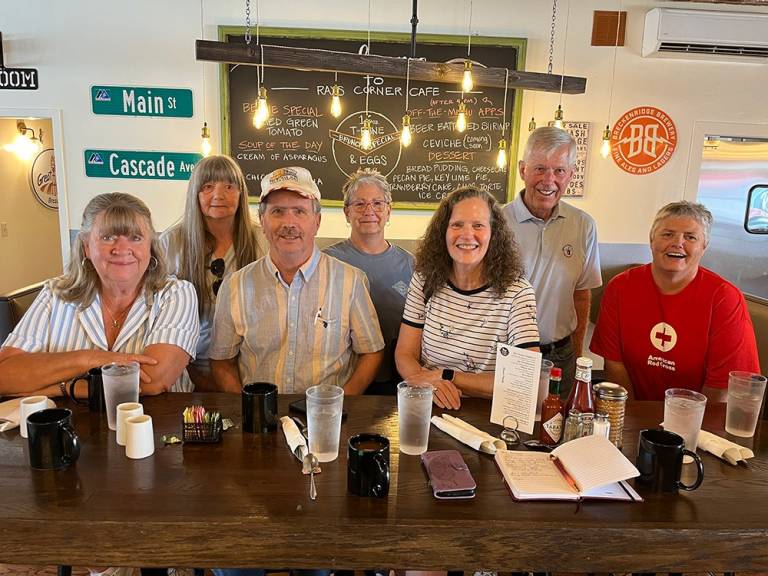 Several people sit together, smiling, as they meet inside a restaurant.