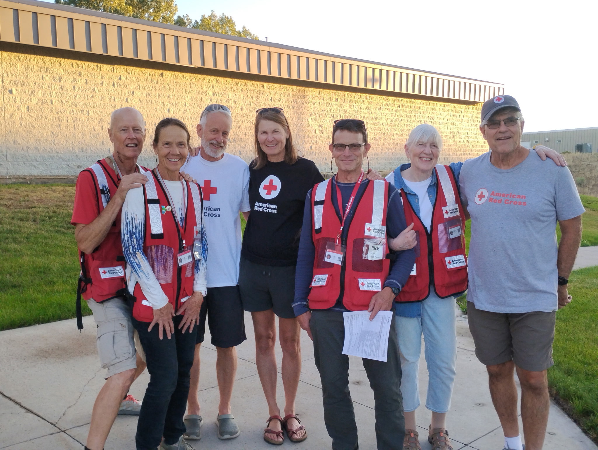 Group of people stand together outside a Red Cross shelter site.