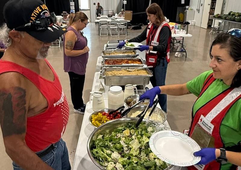 Red Cross volunteer serving a salad to a man