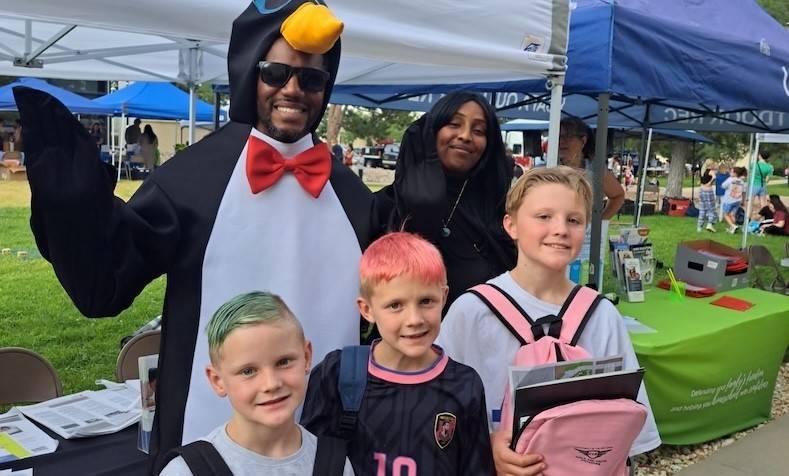 Pedro the Penguin stands with three young students