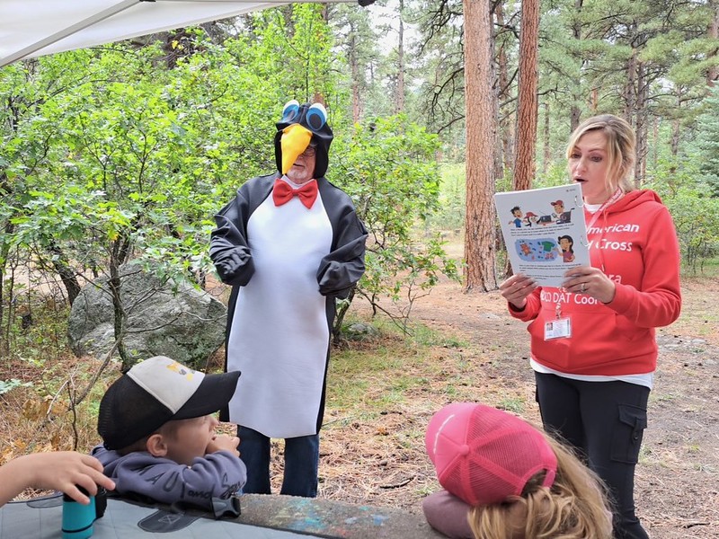 A Red Cross volunteer gives a lesson while another volunteer dressed as Pedro stands next to her.