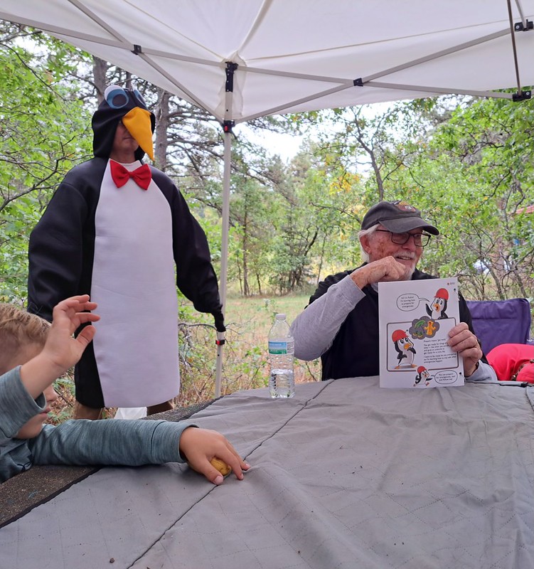 Red Cross volunteer dressed as Pedro the Penguin talks with students