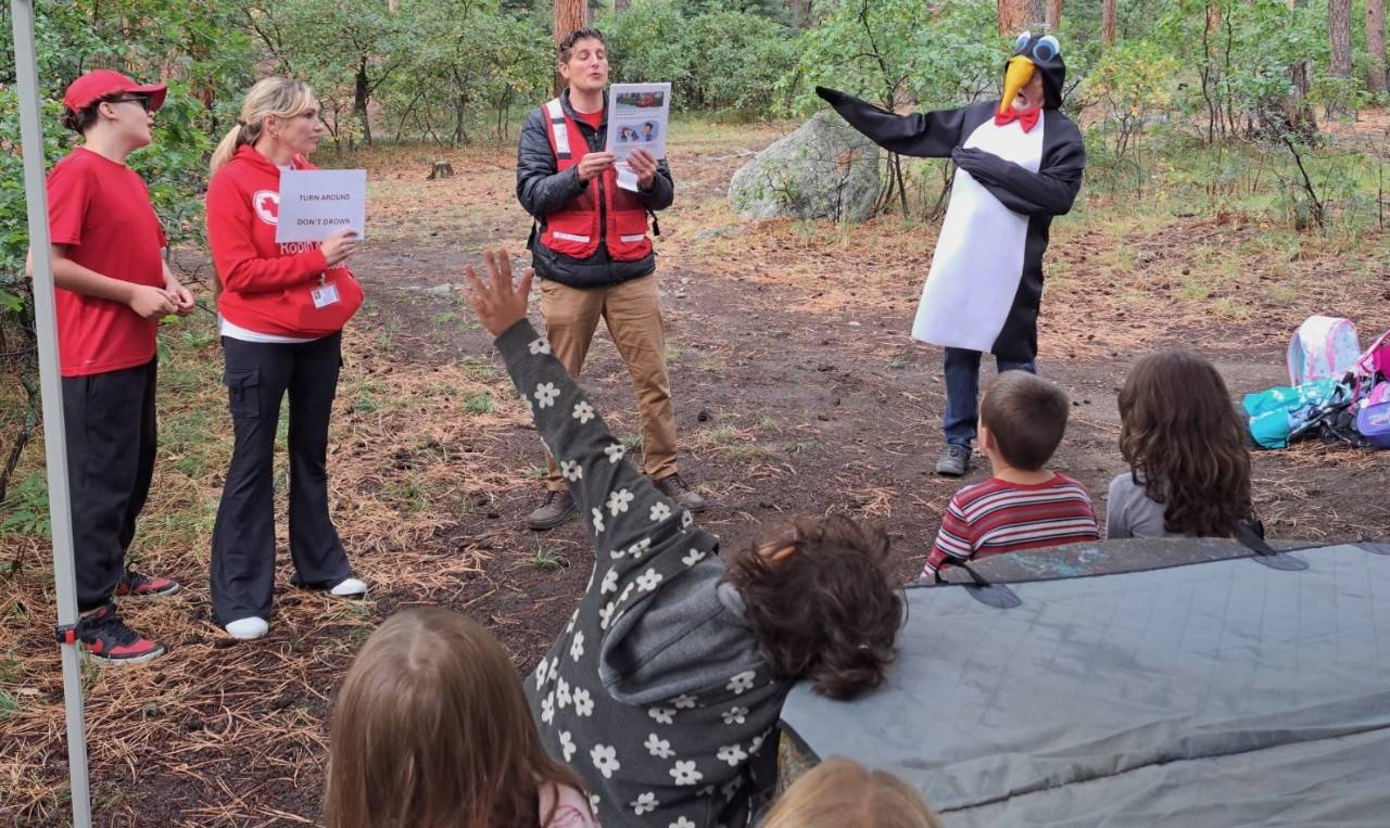 Red Cross volunteer talking to students alongside Pedro in an outdoor setting