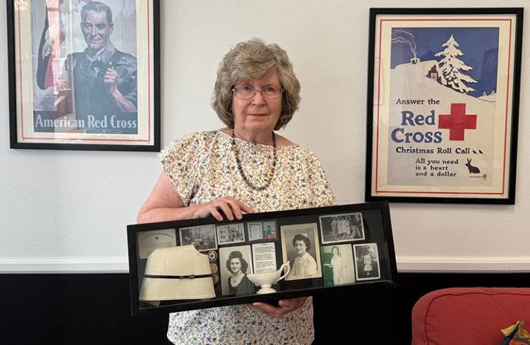 Woman holding a shadow box full of Red Cross mementos