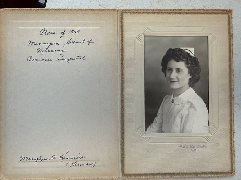A journal with written notes on the inside cover and a woman's photo visible on a page. It is black and white and she is wearing a nurse's outfit.