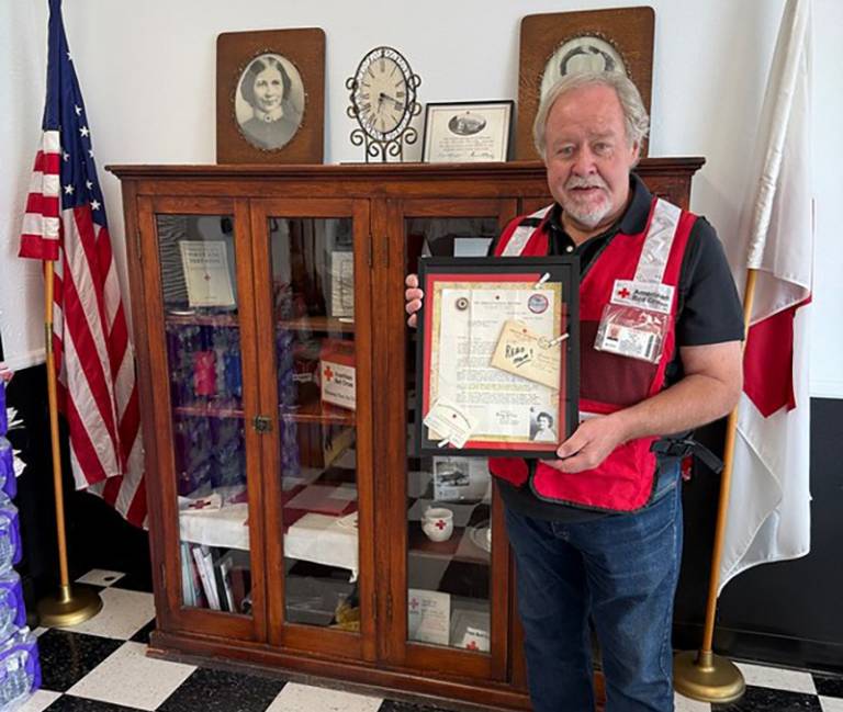 A man holds a shadow box in front of a large cabinet