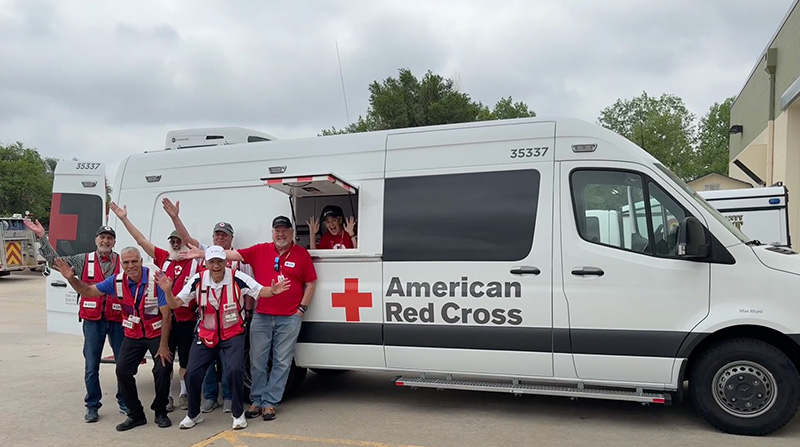 Red Cross volunteers stand in front of a response vehicle