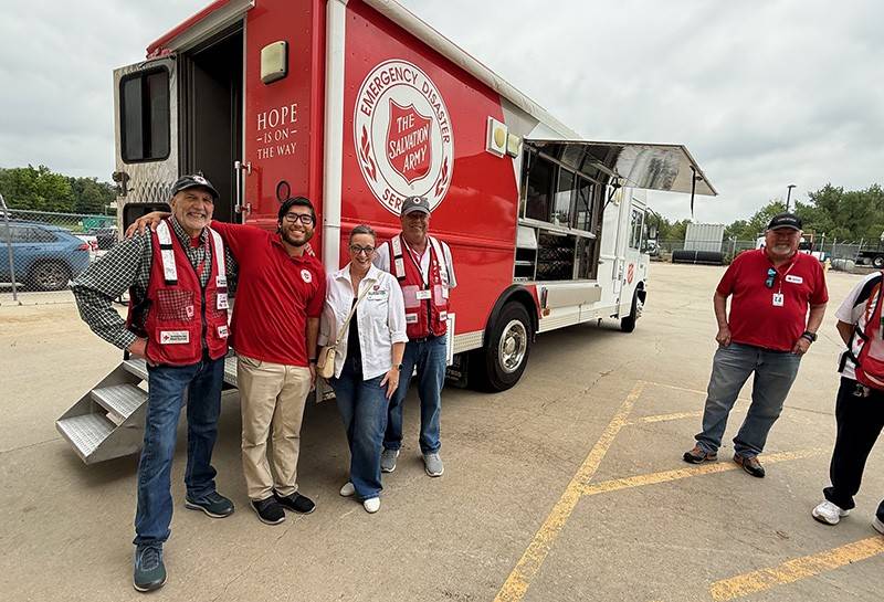 Red Cross volunteers stand in front of a response vehicle