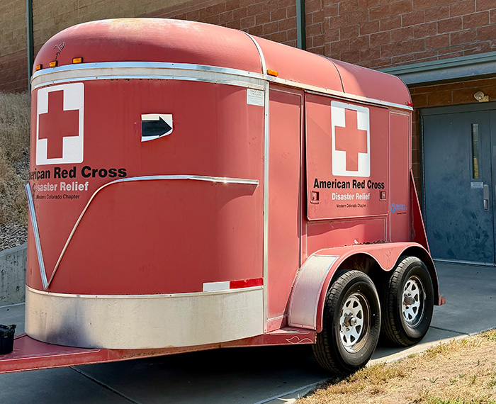A red Red Cross trailer outside of a building