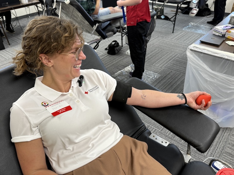A woman in a Red Cross polo prepares to donate blood