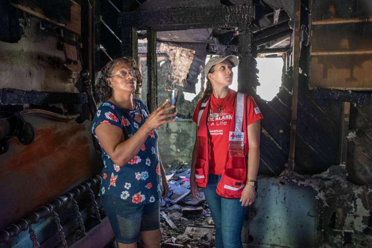 May 18, 2019. Birmingham, Alabama. Jackie Sturdivant shows Red Cross employee Annette Rowland the devastation of an electrical fire that destroyed her family’s home in May 2019. Jackie and her three children survived the fire because of smoke alarms installed by volunteers just three days prior during a Red Cross Sound the Alarm home fire safety and smoke alarm installation event. Here, Jackie points to the location of the smoke alarm that alerted her to the fire.When the fire broke out in the middle of the night, one of the alarms awakened Jackie to alert her three children to safely escape through the front door with their pet dog, Ruby—just like they had discussed as part of their home fire escape plan. “If I didn’t hear that smoke alarm, we probably wouldn’t be with each other right now,” said Jackie, whose youngest son had also recently learned about fire safety at school through the Pillowcase Project, a Red Cross youth preparedness program that’s part of its Home Fire Campaign to reduce fire-related deaths and injuries. Red Cross volunteers also helped Jackie’s family the night of the fire, responding to provide emergency assistance and help with urgent needs like lodging. Photo by Brad Zerivitz/American Red Cross