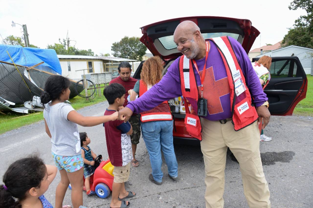 July 16, 2019. Morgan City, Louisiana 
Red Cross disaster workers Hugo Adams and Jodi Wallace offer supplies to Reinerio Guillen and his children. Mr. Guillen s home was damaged by Hurricane Barry and he and his family have been without electricity since Saturday.
Photo by Daniel Cima/American Red Cross