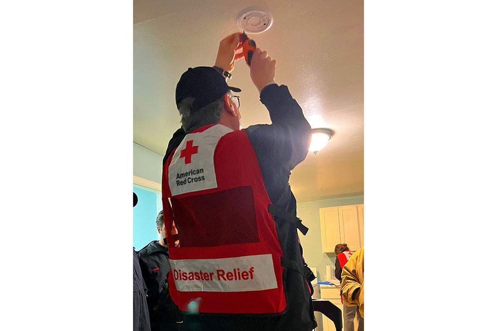 Larry Berman installs a smoke detector on a residential ceiling.