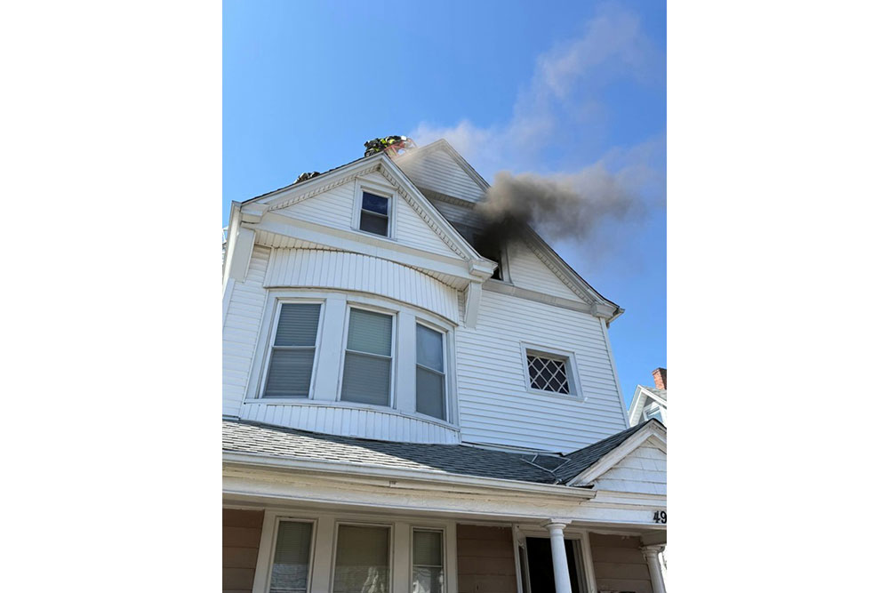 A residential house with visible smoke billowing from the roof.