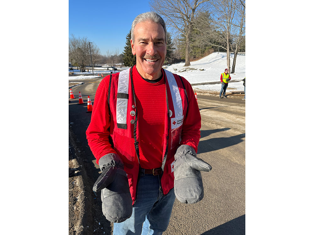 Red Cross volunteer smiling and showing his mittens.