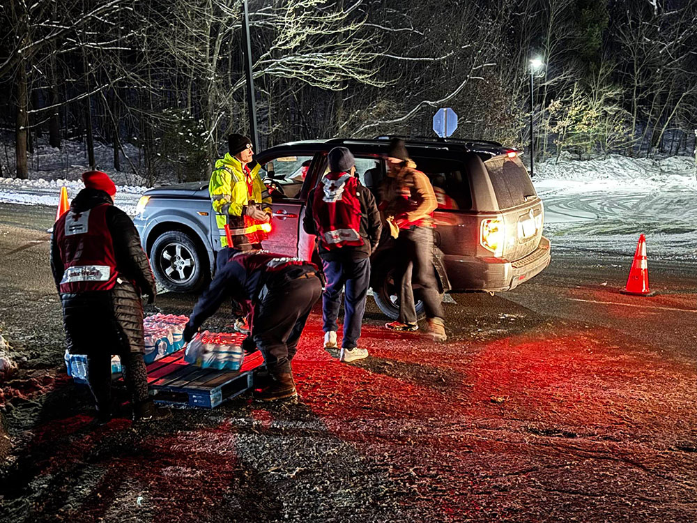 Red Cross volunteers loading a case of water into a truck.