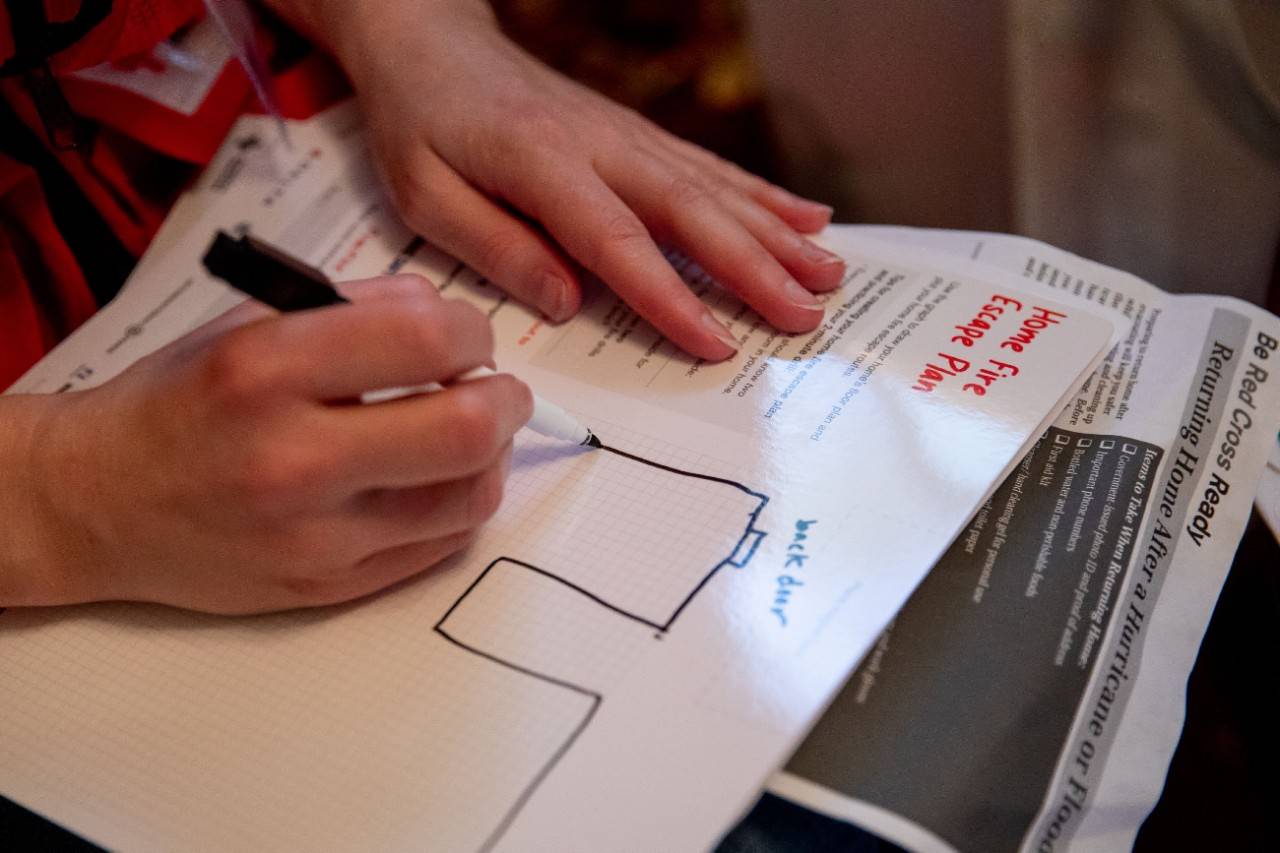 April 28, 2018. 
Wilmington, North Carolina.
Smoke alarm installations at the Sound the Alarm event.
Pictured: American Red Cross Escape Plan

American Red Cross volunteers in Wilmington, North Carolina help residents prepare to survive a  home fire by working with them to create a "Home Fire Escape Plan." The Escape Plan shows family members at least two different ways to exit their home if a fire breaks out. The service is part of an event called "Sound the Alarm," where teams of Red Cross volunteers spend the day installing free smoke alarms in any private home that needs them. This one is in Wilmington, North Carolina, but similar events were held across the country to install smoke alarms in as many homes as possible, and to educate families about how to prevent, and escape from, a home fire.

Photo by Adam Jennings for the American Red Cross.