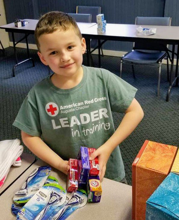 John Leopard standing next to table with Red Cross comfort kits.
