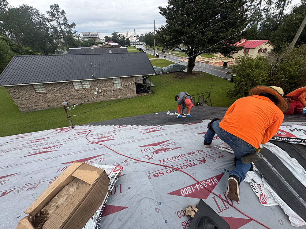 Two men on top of roof working.