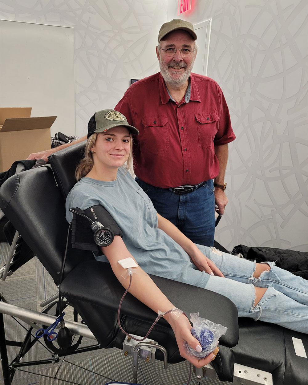 Man standing next to woman giving blood in chair