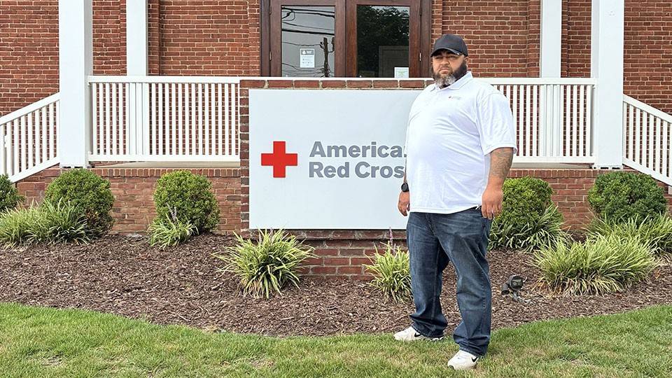 Red Cross staff member Marc Matthews in front of an American Red Cross sign that's in front of a building.