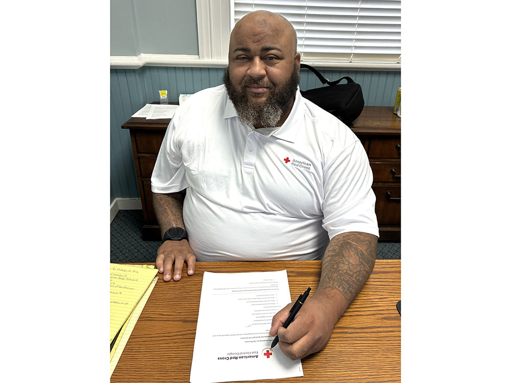 Red Cross staff member Marc Matthews filling out paperwork while sitting at a desk.
