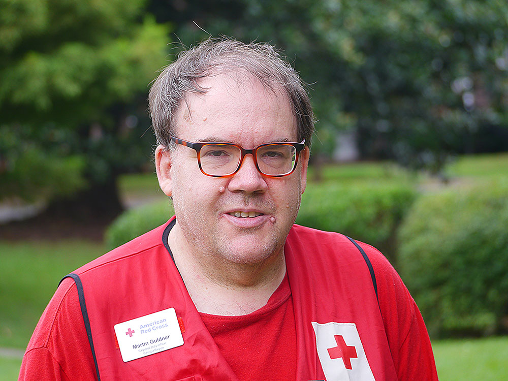 Red Cross volunteer Martin Guldner wearing glasses and a Red Cross vest.