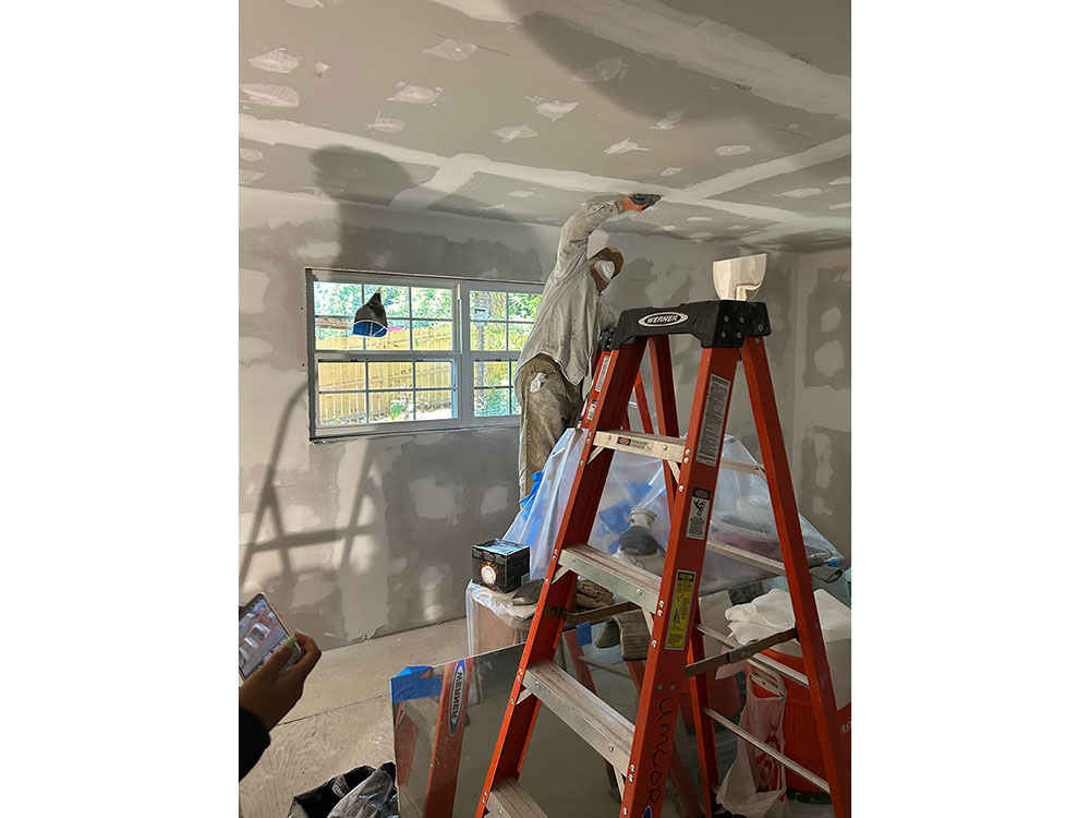 Person working on new drywall in a home.