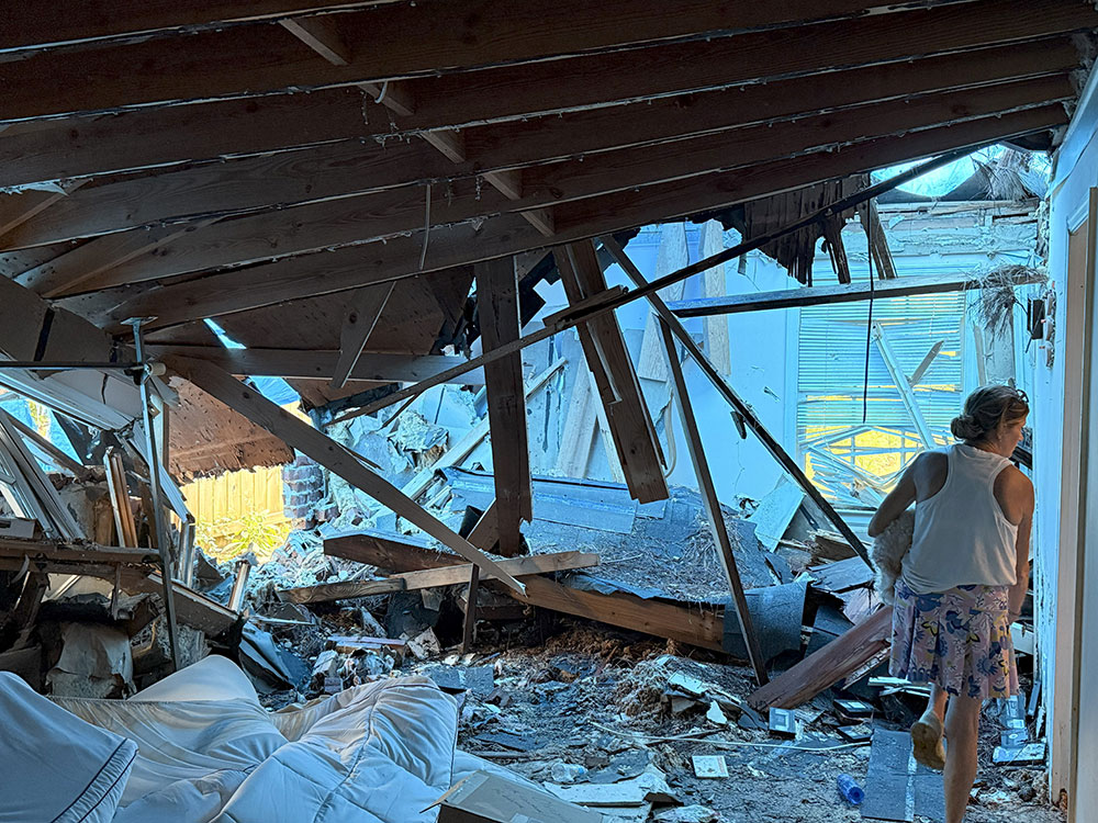 Person walking in room that has been demolished by a hurricane.