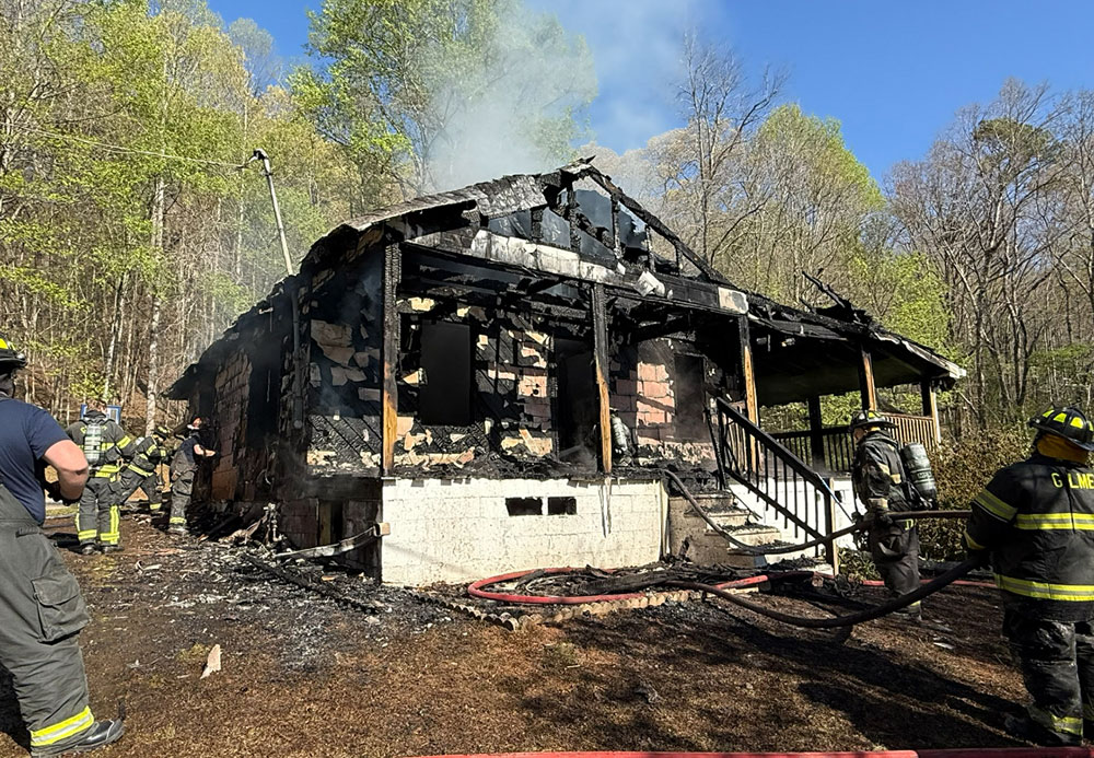 fire fighters standing around burnt house after putting out the flames.