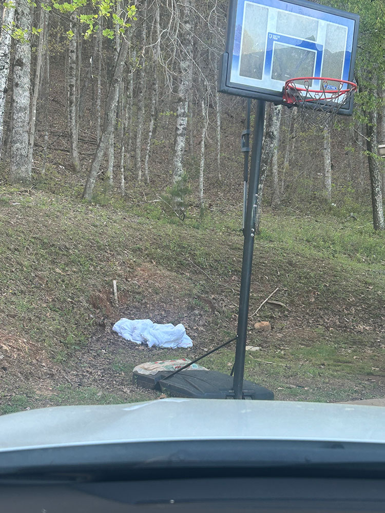 outdoor basketball hoop with small blanket laid on the ground next to it.
