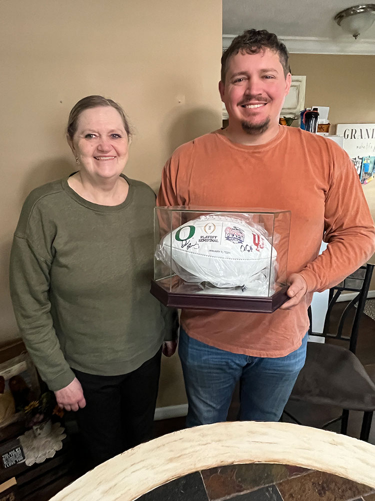 Kathy Kilgore and her son, Kevin, holding his signed Chick-fil-A Peach Bowl football.