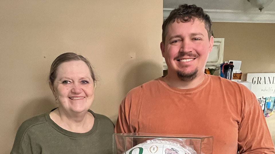 Kathy Kilgore and her son, Kevin, holding his signed Chick-fil-A Peach Bowl football.