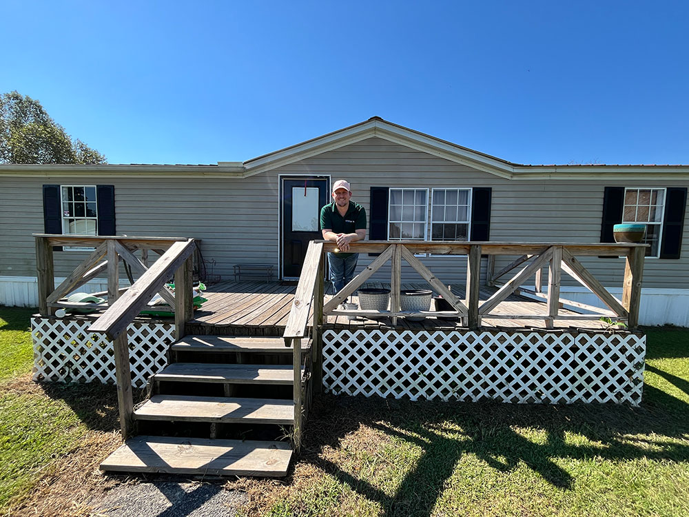 Kent Barker smiling and leaning over railing in front of home.