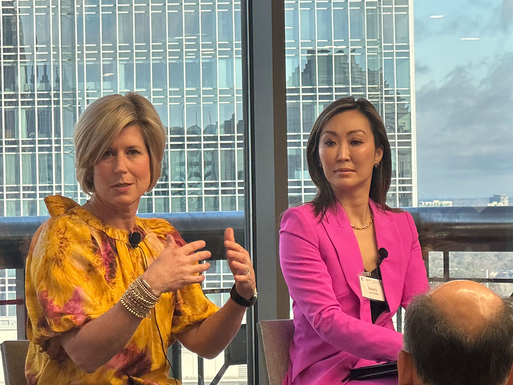 woman in yellow shirt holding up hands, woman in magenta-pink suit