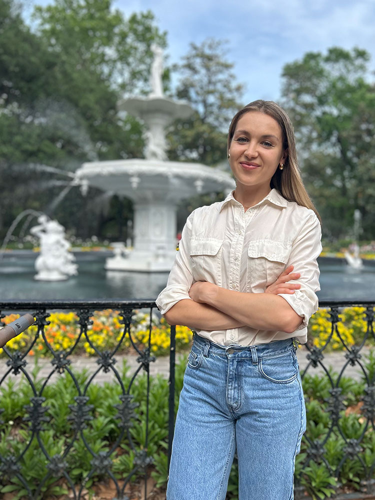 Vira Salzburn poses in front of a large water fountain.